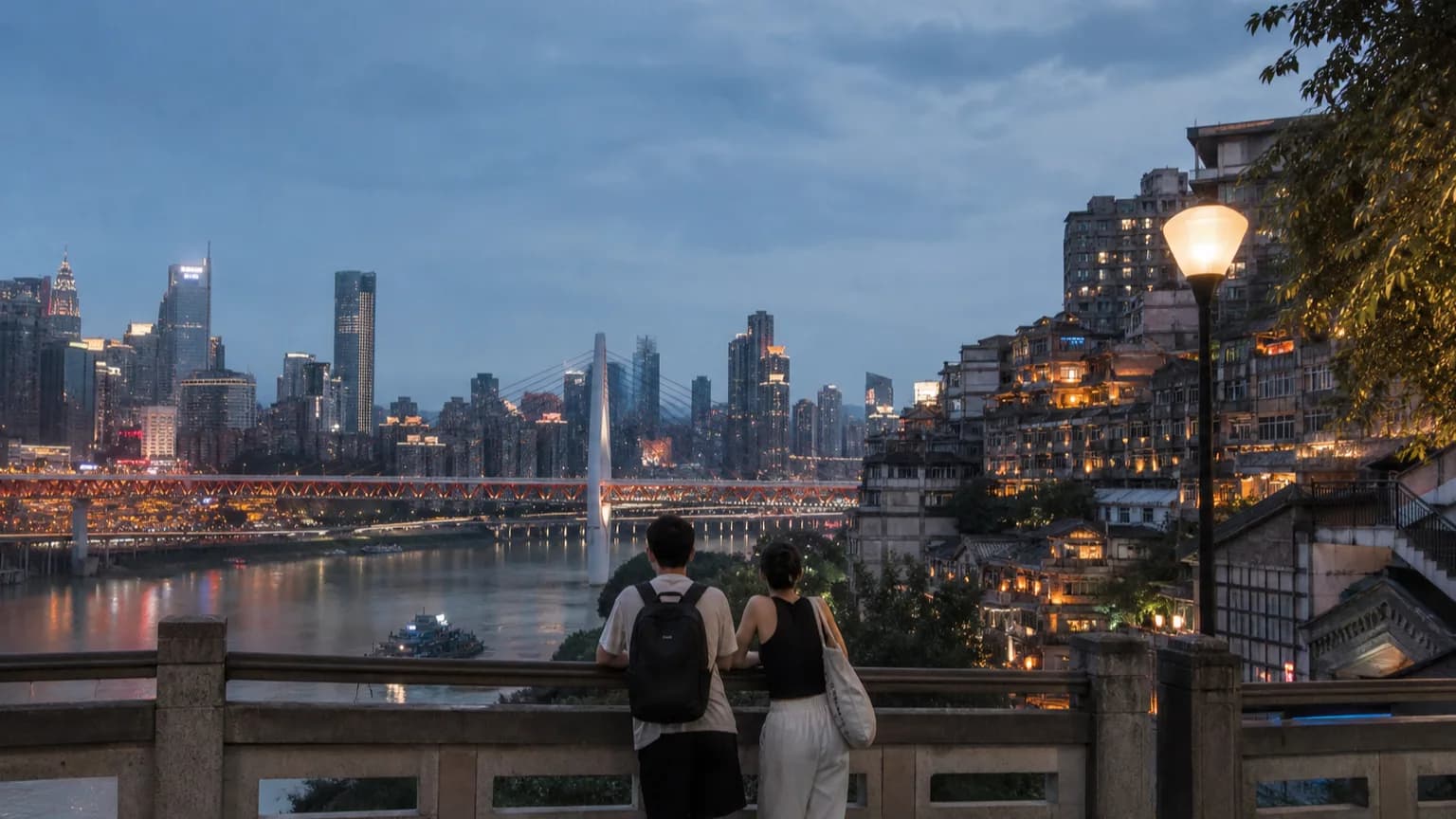 Travelers looking across Chongqing's layered riverside skyline at dusk